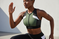 Femme africaine portant la brassière de sport vert kaki et noir avec demi-zip pendant une séance de sport